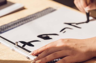 Bir el fırça tutarak ve Asyalı kaligrafisi yazarak kapat