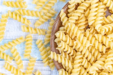 Tahta tabakta çiğ İtalyan fusilli spiral makarna. Ayrıntılı yemek fotoğrafçılığını kapat.