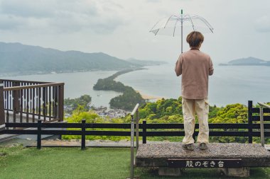 Japonya 'nın üç ikonik manzarasından biri olan Amanohashidate Sandbar' a hayran olan tanımlanamayan bir turist. (Resimdeki metnin çevirisi: izleme platformu)