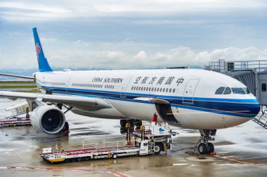 Osaka, Japonya - 05.13.2024: Bir China Southern Airlines Airbus A330-323 uçak ya da Kansai Uluslararası havaalanı pistindeki yolcu köprüsü