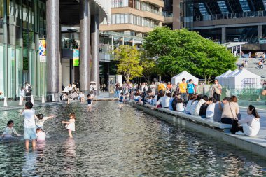 Osaka, Japonya - 05.04.2024: Umekita Plaza 'daki Grand Front Osaka şehir istasyonu yakınlarındaki çeşmede sıcak güneşli bir günün tadını çıkaran aileler ve turistler.