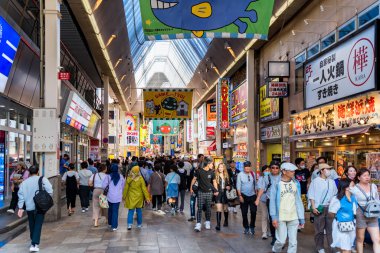 Osaka, Japan - 05.04.2024: Crowd of tourists and locals on a pedestrian shopping street ( Ebisubashisuji Shopping Street) near Namba Osaka, in Japan. clipart