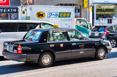 Osaka, Japonya - 05.04.2024: Osaka şehrinin sokaklarında siyah bir taksi. Nissin taksi şirketi..