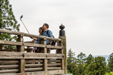 Nara, Japan - 05.06.2024: Asian couple taking a selfie on the balcony of Todai-ji Nigatsu-do temple hall in Nara, Japan. Japanese scenic landscape clipart