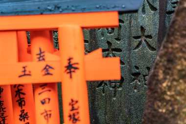 Japonya 'nın Kyoto kentindeki Fushimi Inari Taisha Tapınağı' nda Torii Gates ile küçük bir ibadethane ve yazılı taşlar. (Japonca çeviriler farklı dini nimetlerdir.)