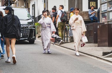 Kyoto, Japonya - 05.07.2024: Geleneksel Japon kimonosu giyen ve Kyoto yaya sokaklarında yürüyen iki genç kız.