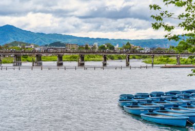 Arashiyama 'nın Katsura Nehri' ndeki limanda mavi botlar. Arka planda Togetsukyo Bridgein, Kyoto. doğa manzarası..