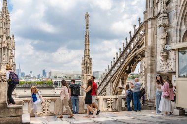 Milan, İtalya - 05.14.2024: Turistler, karmaşık gotik kuleler ve heykellerle çevrili ikonik Duomo di Milano 'nun çatı teraslarında güneşli bir günün tadını çıkarıyorlar.