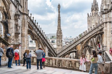 Milan, İtalya - 05.14.2024: Turistler, karmaşık gotik kuleler ve heykellerle çevrili ikonik Duomo di Milano 'nun çatı teraslarında güneşli bir günün tadını çıkarıyorlar.