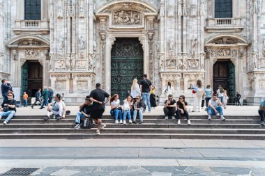 Milan, İtalya - 05.14.2024: Piazza del Duomo 'daki Milan Katedrali' nin (Duomo di Milano) büyük cephesinin önünde canlı bir turist kalabalığı toplandı.