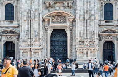 Milan, İtalya - 05.14.2024: Piazza del Duomo 'daki Milan Katedrali' nin (Duomo di Milano) büyük cephesinin önünde canlı bir turist kalabalığı toplandı.