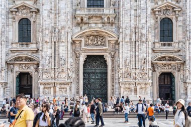 Milan, İtalya - 05.14.2024: Piazza del Duomo 'daki Milan Katedrali' nin (Duomo di Milano) büyük cephesinin önünde canlı bir turist kalabalığı toplandı.