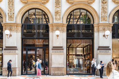 Milan, İtalya - 05.14.2024: Alışveriş ve turistler, Milano 'daki tarihi Galleria Vittorio Emanuele II' de bulunan zarif Bottega Veneta butiğinin önünden geçtiler