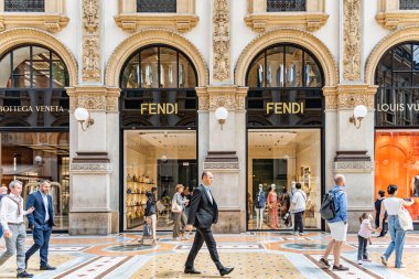 Milan, İtalya - 05.14.2024: Alışveriş ve turistler, İtalya 'nın Milano kentinde bulunan zarif Galleria Vittorio Emanuele II' nin içinde Fendi, Bottega Veneta ve Louis Vuitton gibi lüks moda butiklerinin önünden geçtiler.
