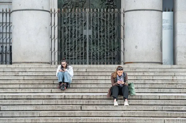 Madrid, İspanya - 03.10.2025: Almudena Katedrali girişindeki basamaklarda dinlenen iki kız veya kadın