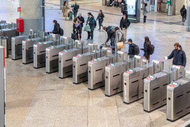 Madrid, İspanya - 10 Mart 2025: İspanya 'nın en işlek taşıma merkezlerinden biri olan Atocha Tren İstasyonu' ndaki modern elektronik turnikelerde geçiş kartlarını tarayan yolcular