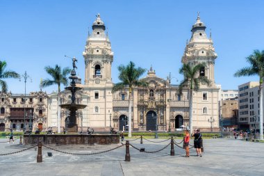 Lima, Peru - 11 Mart 2025: Güneşli bir günde arka planda Lima Katedrali ile Plaza Mayor 'da yürüyen turistler.