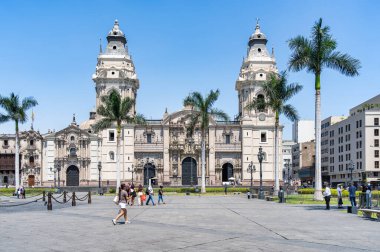 Lima, Peru - 11 Mart 2025: Güneşli bir günde arka planda Lima Katedrali ile Plaza Mayor 'da yürüyen turistler.