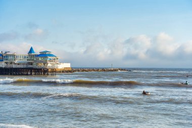 Lima, Peru 12 Mart 2025: Lima 'da Pasifik Okyanusu' nun kayalık kıyılarında sörf yapan sörfçüler