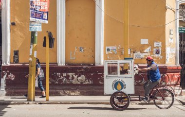 Ica, Peru - 13 Mart 2025: Perulu aperatifler satan yerel bir bisikletçi ile sokak hayatı