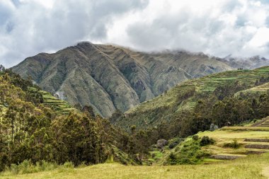 Peru, Chinchero Arkeoloji Alanı 'nda yemyeşil terasları ve sisli And Dağları olan manzaralı bir yer.