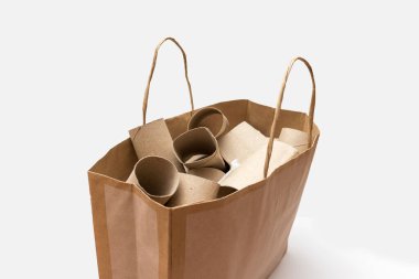 Beyaz arka planda boş tuvalet kağıdı ruloları olan karton bir çanta. Geri dönüşüm ve tüketim kavramı