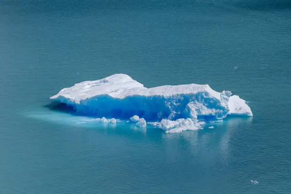 Ice block floating in blue water and merlting away.