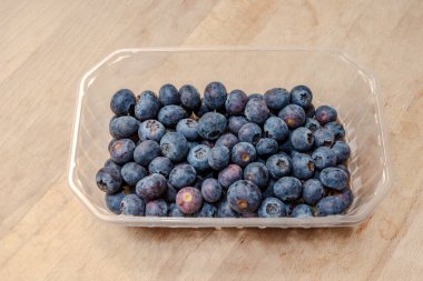 Böğürtlenli, ahşap yüzeydeki plastik kapta en üstten..