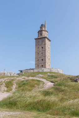 İspanya, A coruna 9.6.2025: Güneşli havanın tadını çıkaran ve Herkül Kulesi 'nin etrafında yürüyen insanlar.