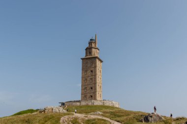 İspanya, A coruna 9.6.2025: Güneşli havanın tadını çıkaran ve Herkül Kulesi 'nin etrafında yürüyen insanlar.