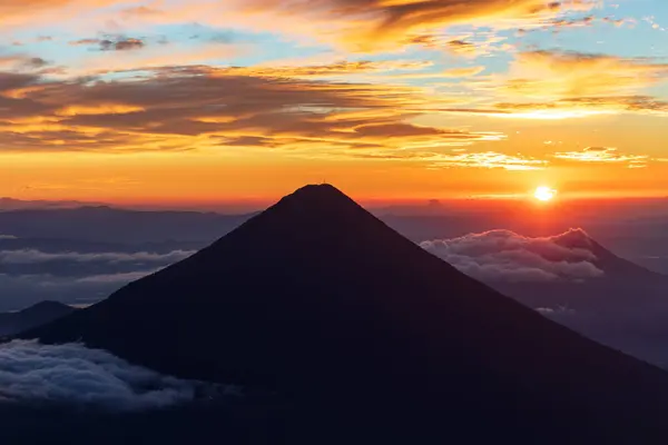 Volkan de agua 'nın silueti alevli turuncu gündoğumunda ya da gün batımında volkan de acatenango, Guatemala' nın tepesinden görüldü..