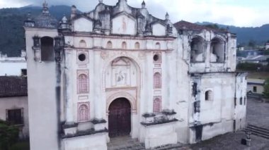 Parkın ortasında, bir kilise manzaraya hakim olurken, ufukta görkemli bir volkan yükseliyor, ilahi ve doğal olanı etkileyici bir resimde kaynaştırıyor..