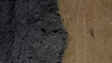 Kuru otların arasında erimiş bir kayayı gösteren hava görüntüsü şaşırtıcı bir doğal karşıtlık yaratıyor. Sahne, erimiş kayanın sert ve sıcak yüzeyi ile kuru dokusu arasındaki etkileşimi vurgular.