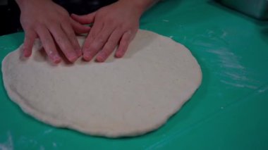 Zanaatkar pizza hamurundaki detayların özenle halledilmesi. Uzman eller şekli ve dokuyu ayarlar, içeriği eklemeden önce hamurun mükemmel olmasını sağlar.
