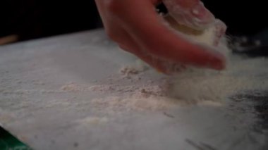 Metal bir küreğe un serpme işlemi, pizza hamuru almaya hazırlamak. Bu önemli adım hamurun yapışmasını engelliyor ve fırına geçmesini kolaylaştırıyor. Pizzaların zanaatkarca hazırlanmasında önemli bir detay.