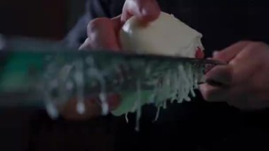 Mutfak yüzeyine taze mozzarella ekleyerek peynir rendesinin detaylı bir yakın çekimini keşfedin. Görüntü rendelenmiş peynirin dokusunu ve kayganlığını vurgular, tazeliğini ve içeriğinin kalitesini vurgular.