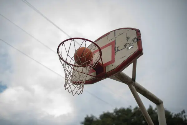 Gökyüzünün arka planında top olan basketbol potası.
