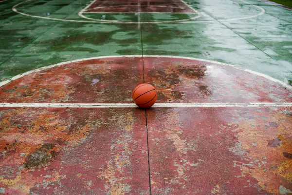 Basketbol topu sahanın ortasında, ayrıntılı bir perspektifte yakalandı. Manzara, sahanın zeminindeki topun konumunu ve sahanın düzenini vurguluyor.