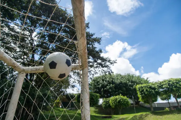 Topun toprak bir futbol sahasında gol attığı heyecanlı bir an.
