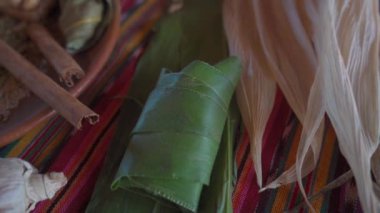 Yeşil bir yaprağa sarılı bir tamale 'nin nihai sonucu, geleneksel yemek pişirmede kullanılan tekniği ve dikkati vurguluyor..