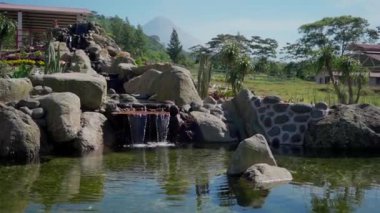 Bahçede süslemeli yapay bir çeşme, nazikçe akan su ve sakin ve ferahlatıcı bir ortam yaratıyor.