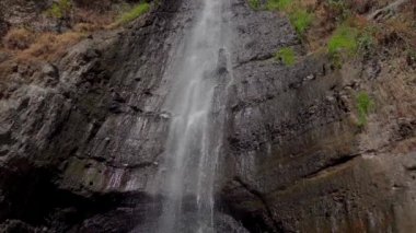 Suyun hareketi bir şelaledeki kaya duvarından zorla iniyor. Su, kayanın farklı seviyelerinden ve çıkıntılarından geçerek dinamik bir akış düzeni oluşturur.