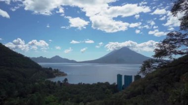 Görkemli volkanlarla çevrili Atitlan Gölü 'nün çarpıcı panoramik manzarası. Manzara gölün sakin sularında gökyüzünün parlak yansımasıyla karakterize edilir.