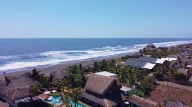 Arka planda deniz olan bir sahil evinin panoramik manzarası tüm ihtişamıyla kıyı manzarasını gösteriyor.