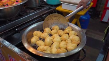 Sıcak yağdan taze kızarmış buelolar çıkıyor, altın ve çıtır çıtır dokularını gösteriyor.