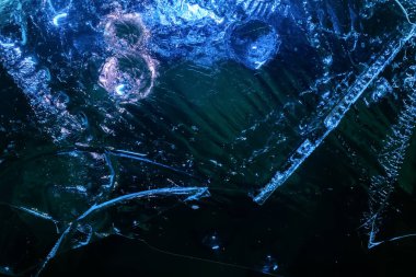 Close up photo texture of frozen dark and cracked water surface.