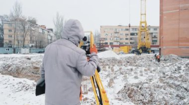 İnşaat İşçisi İnşaat Alanındaki Yatay ve Dikey Düzlemlerdeki Açıları Ölçmek İçin Optik Araştırma Aracı Kullanıyor. İnceleme Kullanan Mimari.