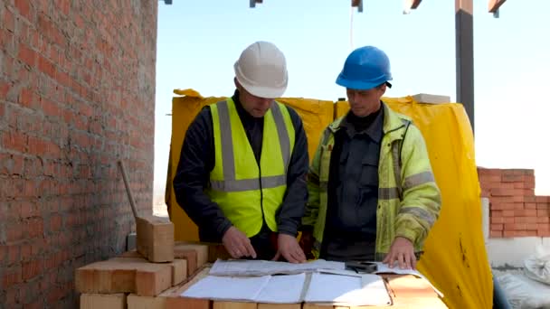 两名建筑工人在工地上看蓝图工程计划 建筑工地上的建筑商看图 — 图库视频影像