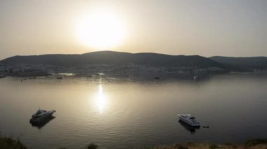 Eski Avrupa 'daki dağın tepesinden gün batımı görüntüsü deniz limanında güneşin yansıması. Sakin deniz, gün batımında gökyüzü ve bulutların arasında güneş..