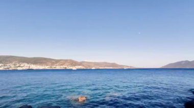 Sakin deniz, dağlar, denizde süzülen beyaz yat, güneşli bir gün.